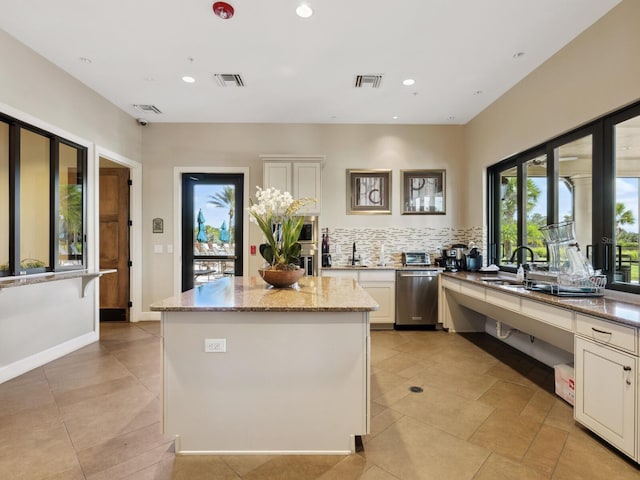 kitchen featuring light stone counters, dishwasher, decorative backsplash, white cabinets, and sink