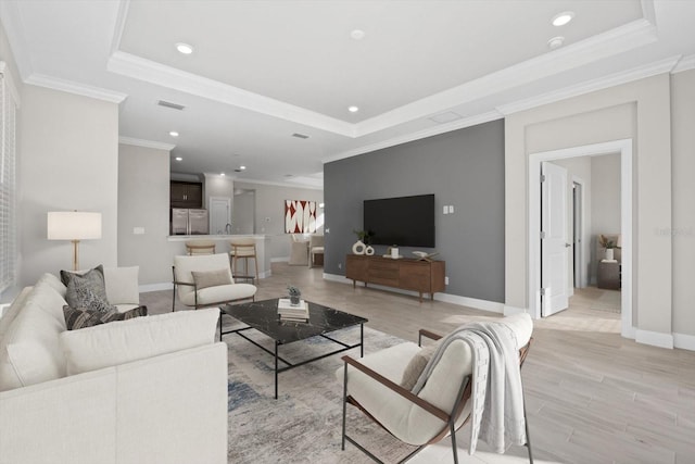 living room with a tray ceiling, light hardwood / wood-style flooring, and crown molding