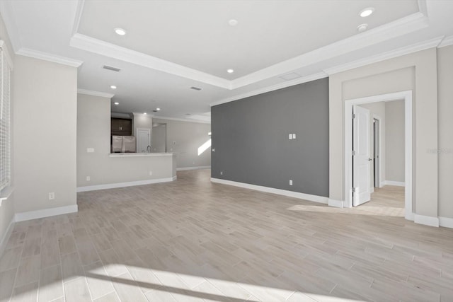 unfurnished living room featuring a tray ceiling, light hardwood / wood-style flooring, and ornamental molding