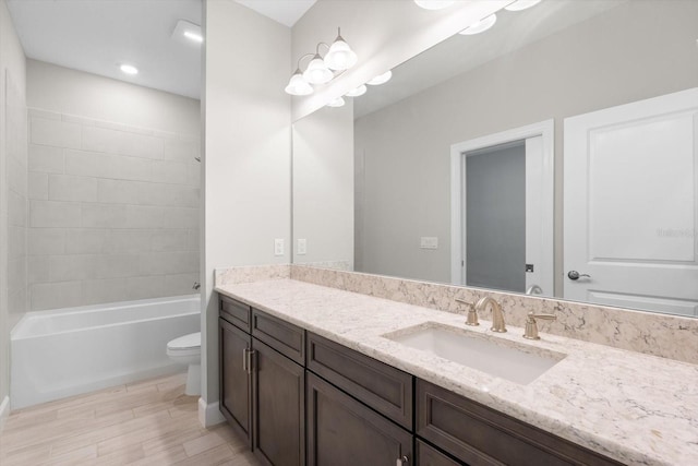 full bathroom with vanity, hardwood / wood-style flooring, toilet, and tiled shower / bath combo