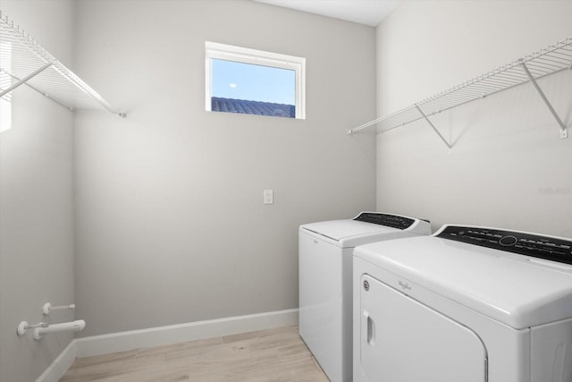 washroom with washing machine and clothes dryer and light hardwood / wood-style floors