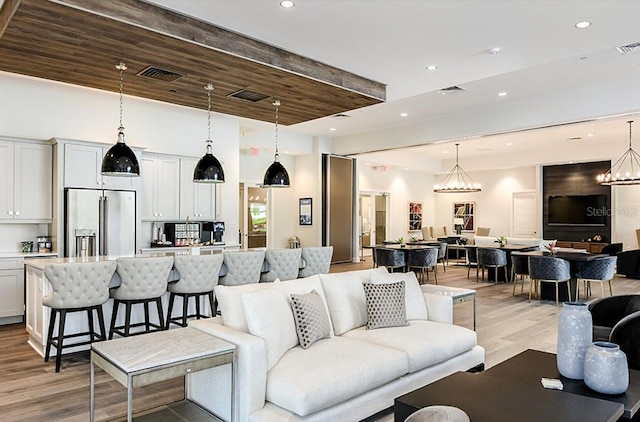 living room with light wood-type flooring, an inviting chandelier, and wooden ceiling