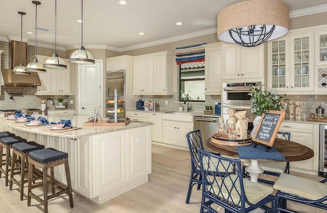 kitchen with light stone countertops, sink, stainless steel appliances, a center island with sink, and light wood-type flooring