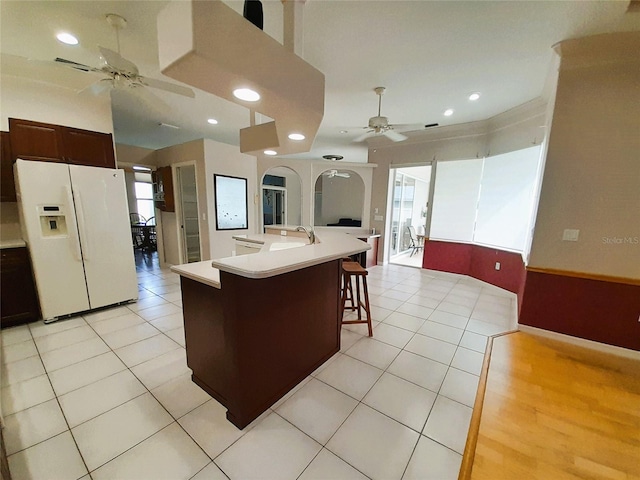 kitchen featuring white fridge with ice dispenser, a center island with sink, sink, and ceiling fan