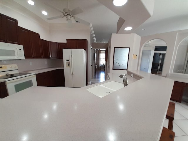 kitchen featuring sink, a breakfast bar area, ceiling fan, a kitchen island, and white appliances