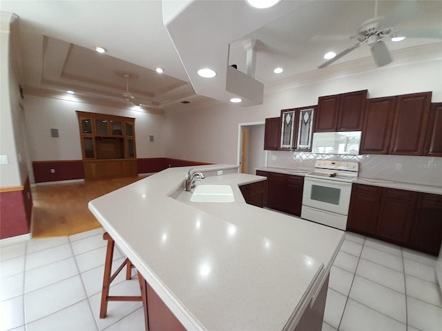 kitchen featuring sink, a large island, a kitchen breakfast bar, a raised ceiling, and white appliances