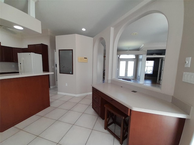 kitchen with light tile patterned floors, crown molding, and white refrigerator with ice dispenser