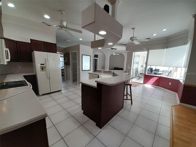 kitchen featuring light tile patterned flooring, a breakfast bar area, white appliances, ceiling fan, and a center island