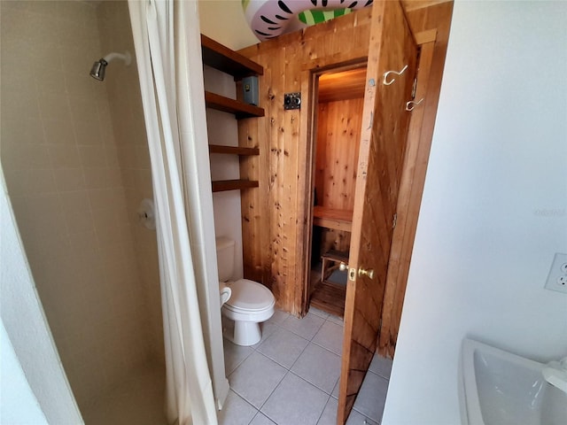 bathroom featuring toilet, wooden walls, and tile patterned floors