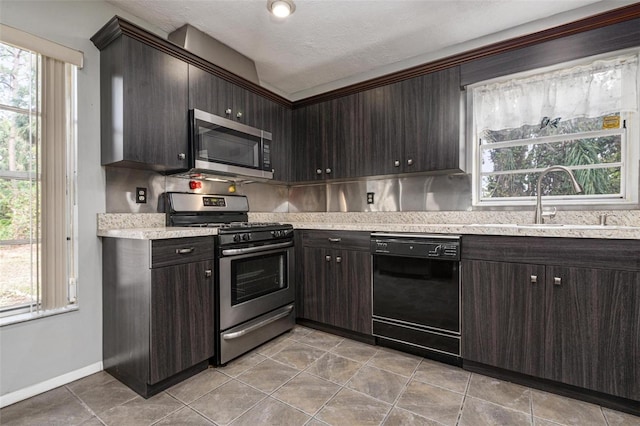 kitchen featuring appliances with stainless steel finishes, a textured ceiling, dark brown cabinets, and sink