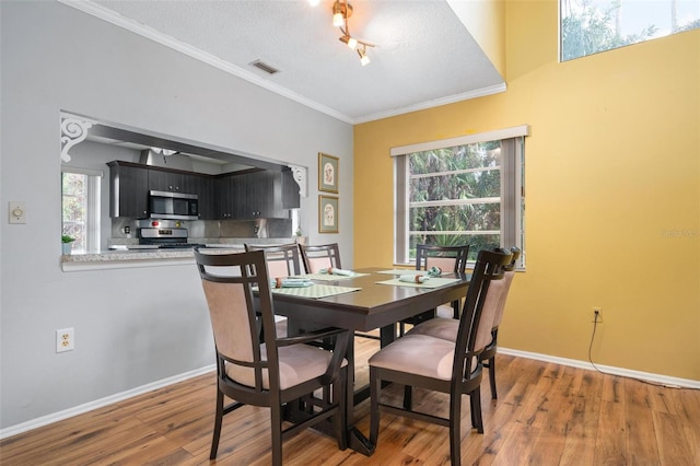 dining room featuring crown molding, dark hardwood / wood-style flooring, and a textured ceiling