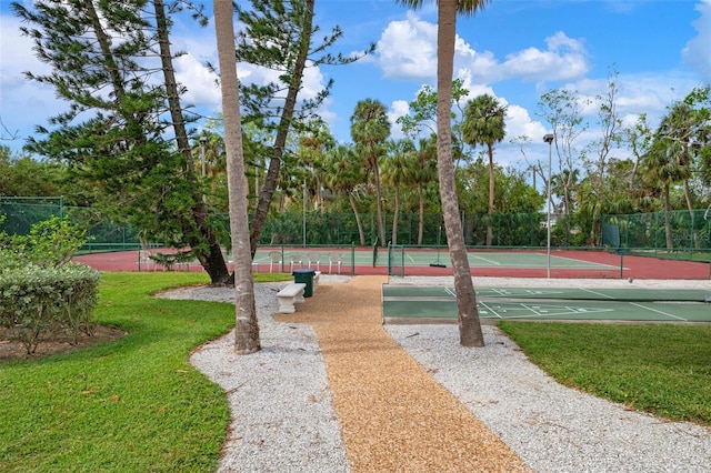 view of home's community with a lawn and tennis court