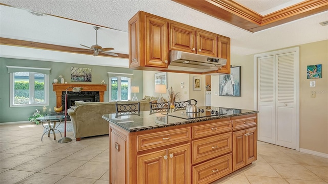 kitchen featuring ceiling fan, dark stone countertops, light tile patterned flooring, a high end fireplace, and black electric cooktop