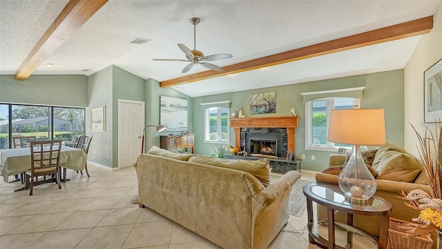 living room featuring a textured ceiling, a high end fireplace, vaulted ceiling with beams, light tile patterned flooring, and ceiling fan