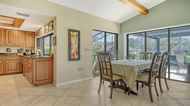 dining area featuring sink, a textured ceiling, light tile patterned floors, and vaulted ceiling with beams