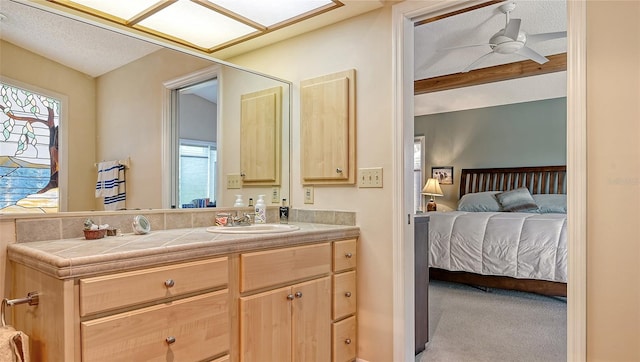 bathroom with ceiling fan, a textured ceiling, vanity, and lofted ceiling with beams