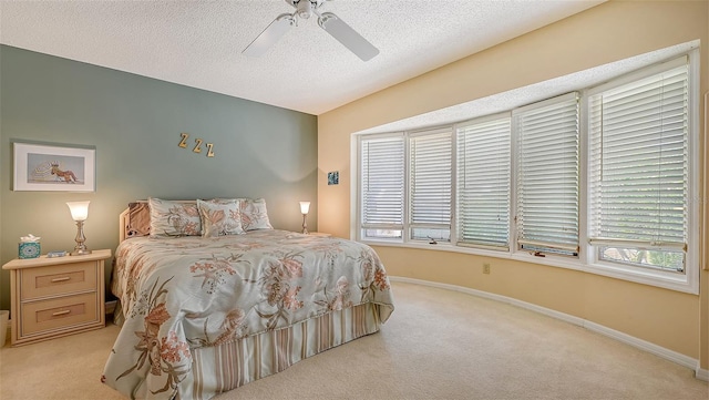 bedroom featuring ceiling fan, light carpet, multiple windows, and a textured ceiling