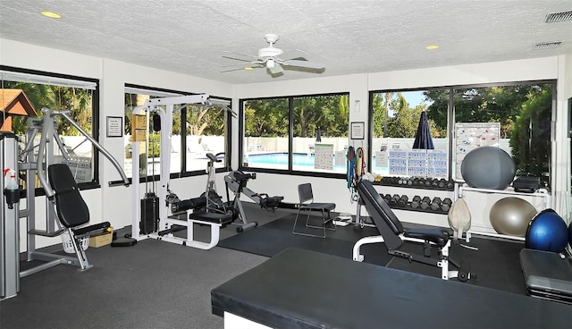 gym featuring ceiling fan, a healthy amount of sunlight, and a textured ceiling