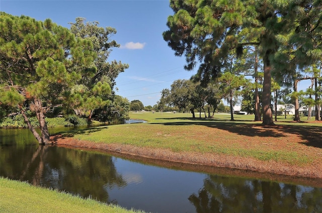 surrounding community with a water view and a lawn