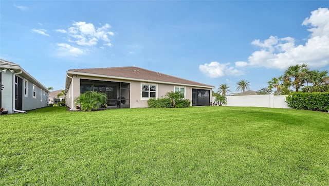 rear view of property featuring a lawn and a sunroom