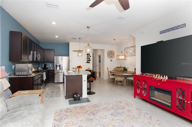 tiled living room with sink and ceiling fan with notable chandelier