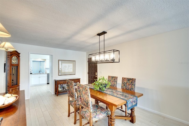 dining space with light wood-type flooring, a textured ceiling, and sink