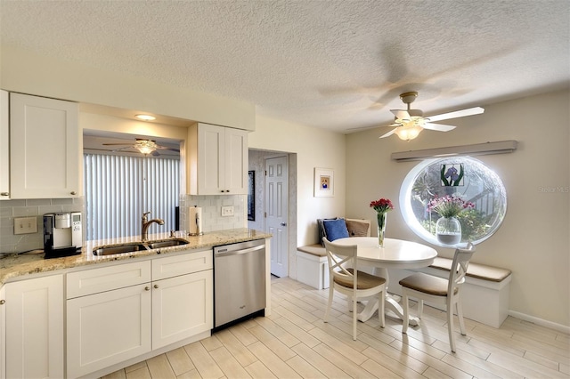 kitchen featuring dishwasher, white cabinets, sink, decorative backsplash, and light stone counters