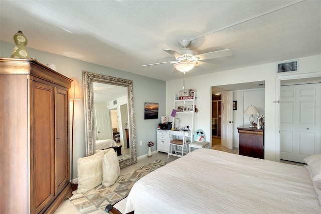 bedroom featuring a textured ceiling, ceiling fan, and multiple closets