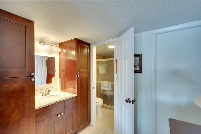 bathroom featuring walk in shower, vanity, a textured ceiling, and toilet