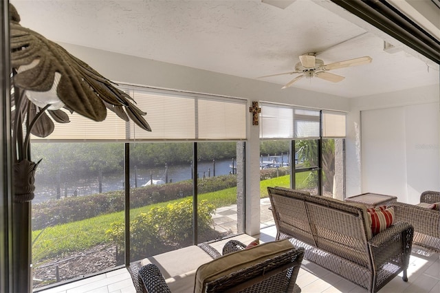 sunroom featuring ceiling fan and a water view