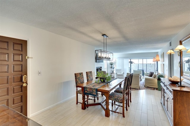 dining area featuring light wood-type flooring, an inviting chandelier, and a textured ceiling