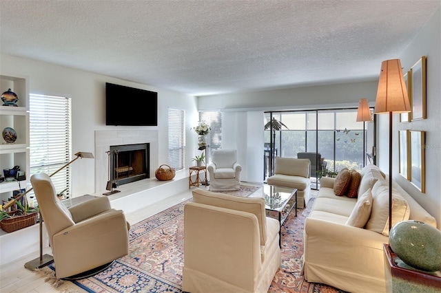 living room with light hardwood / wood-style floors, a high end fireplace, and a textured ceiling