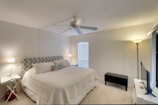 bedroom with ceiling fan, light hardwood / wood-style flooring, and a textured ceiling