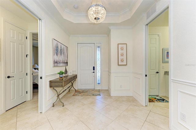 foyer featuring a chandelier, a raised ceiling, and ornamental molding