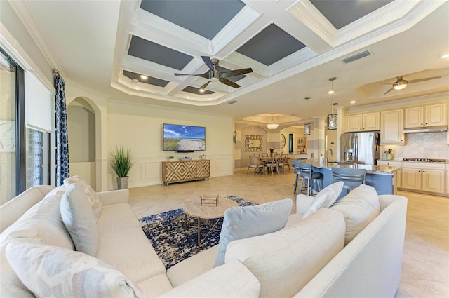 living room with beamed ceiling, ceiling fan, ornamental molding, and coffered ceiling