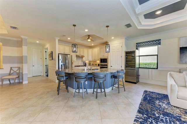 kitchen with hanging light fixtures, wine cooler, crown molding, appliances with stainless steel finishes, and light stone counters