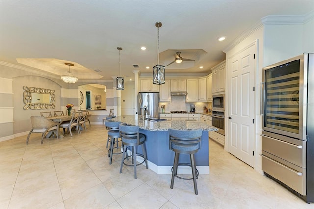 kitchen featuring light stone countertops, appliances with stainless steel finishes, a kitchen island with sink, sink, and pendant lighting