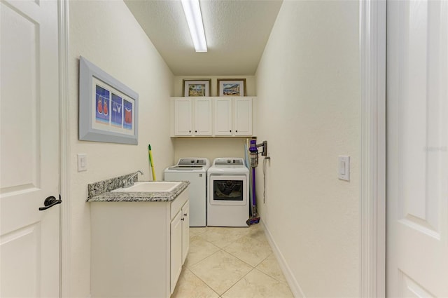 laundry room featuring cabinets, sink, washer and dryer, light tile patterned floors, and a textured ceiling