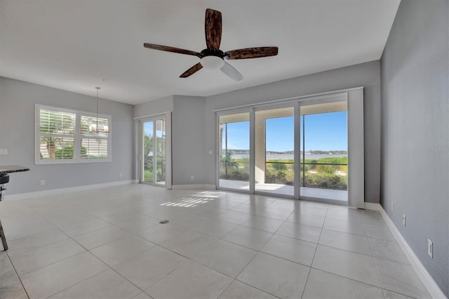 unfurnished room featuring ceiling fan with notable chandelier and light tile patterned floors