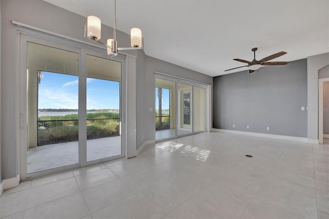 empty room with ceiling fan with notable chandelier and light tile patterned floors