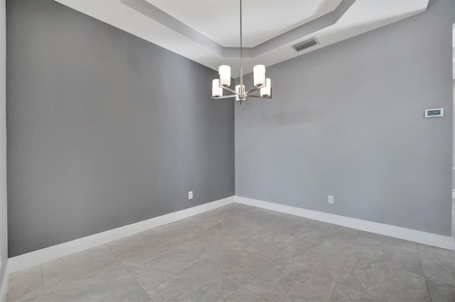 empty room featuring a tray ceiling and an inviting chandelier