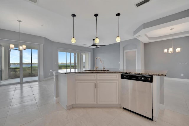 kitchen featuring stainless steel dishwasher, light stone counters, sink, and an island with sink