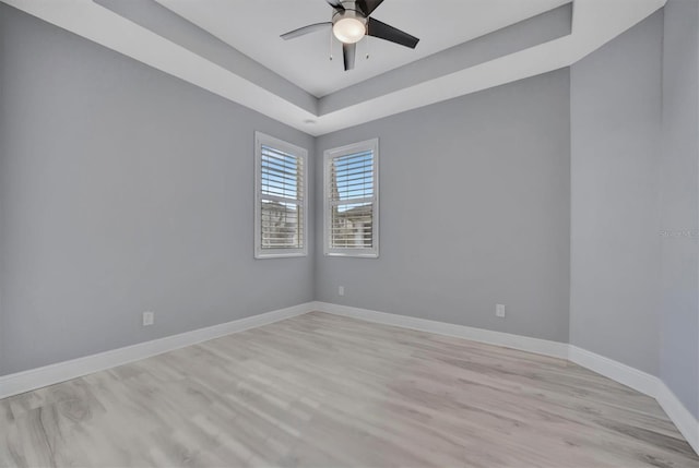 spare room featuring light wood-type flooring, ceiling fan, and a tray ceiling