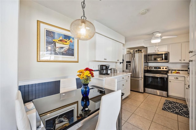 kitchen with white cabinetry, appliances with stainless steel finishes, backsplash, light tile patterned floors, and pendant lighting