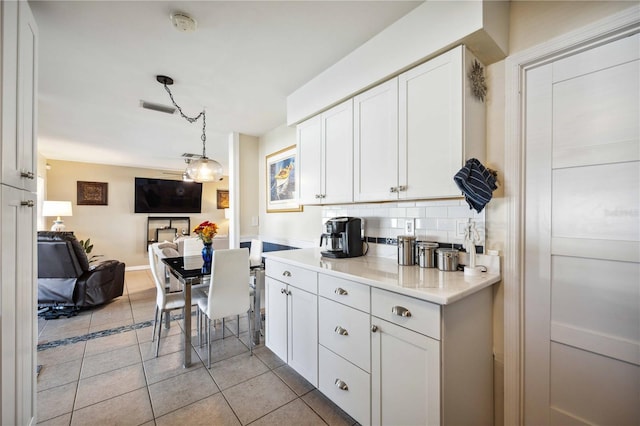 kitchen with decorative light fixtures, decorative backsplash, light tile patterned floors, and white cabinets