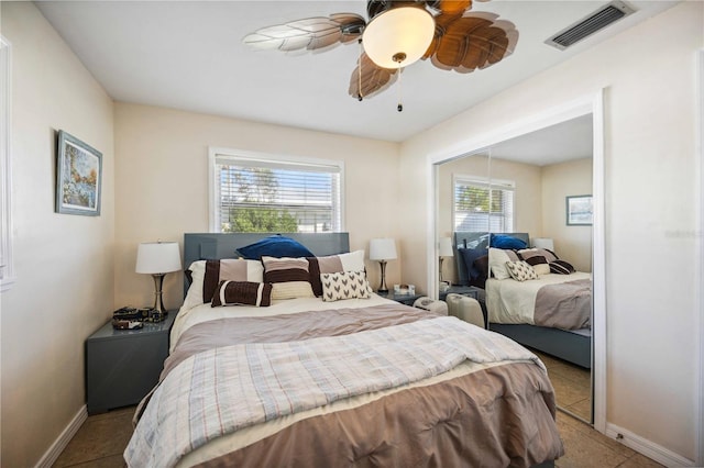 bedroom with light tile patterned floors, ceiling fan, multiple windows, and a closet