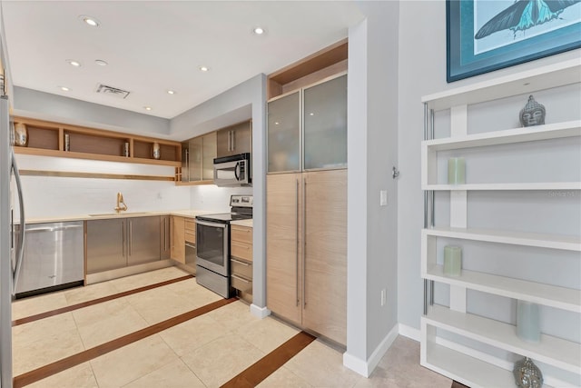 kitchen featuring sink, light tile patterned floors, backsplash, and appliances with stainless steel finishes