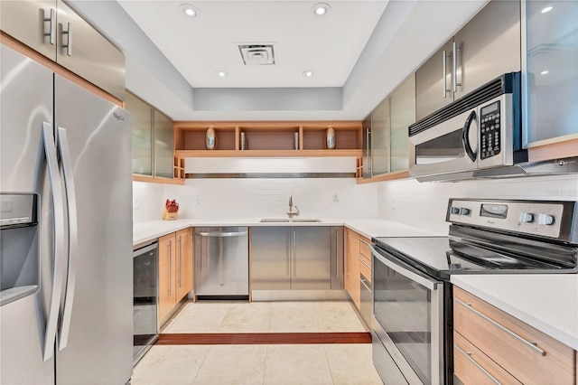 kitchen with appliances with stainless steel finishes, light tile patterned flooring, tasteful backsplash, and sink