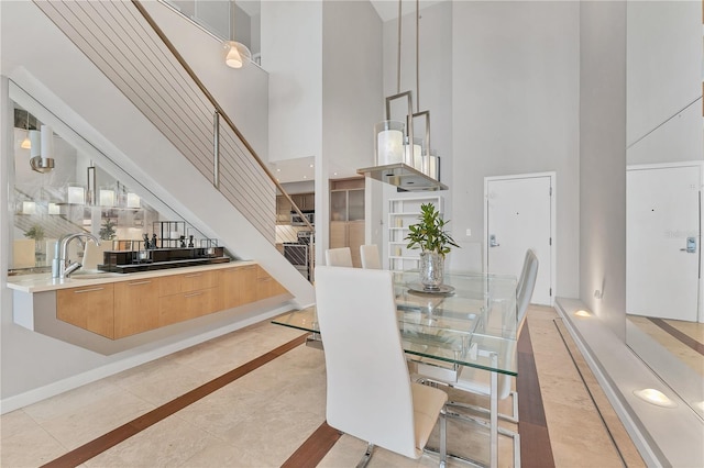 tiled dining space featuring sink and a towering ceiling