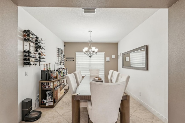 dining space with light tile patterned floors, a textured ceiling, and a notable chandelier